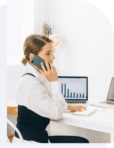 a woman uses a cell phone while sitting at a desk